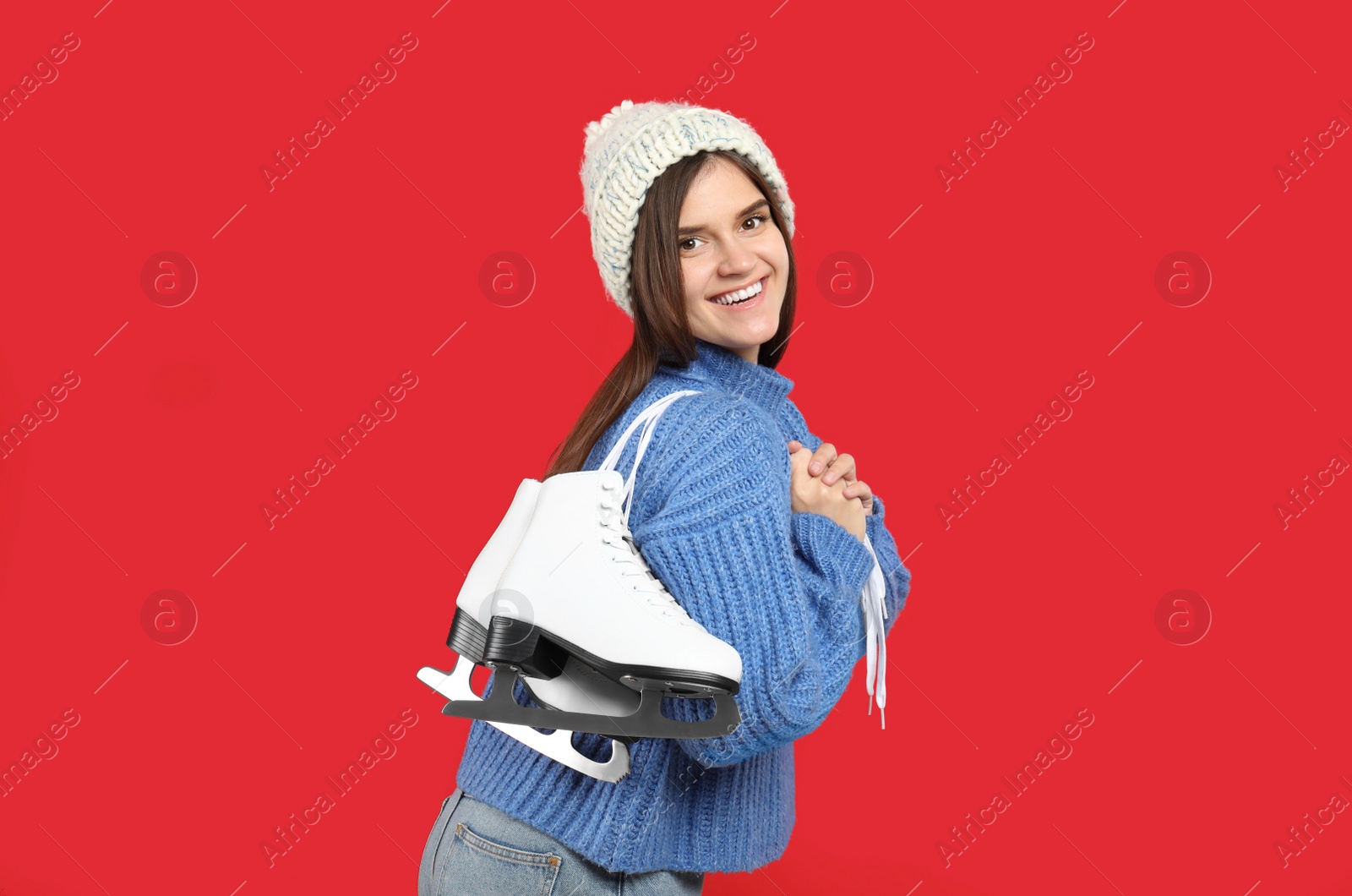 Photo of Happy woman with ice skates on red background