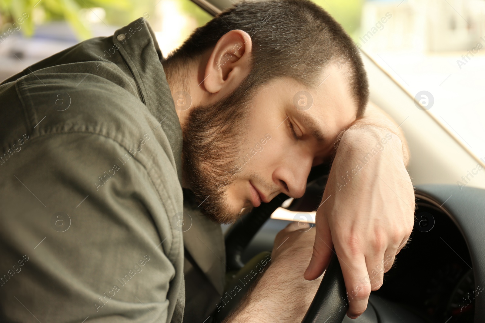 Photo of Tired man sleeping on steering wheel in his car