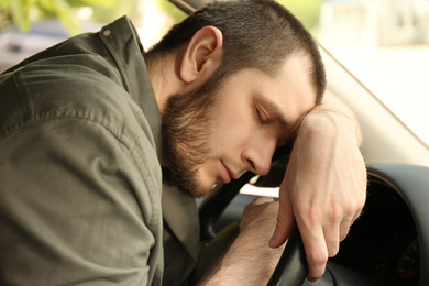 Photo of Tired man sleeping on steering wheel in his car