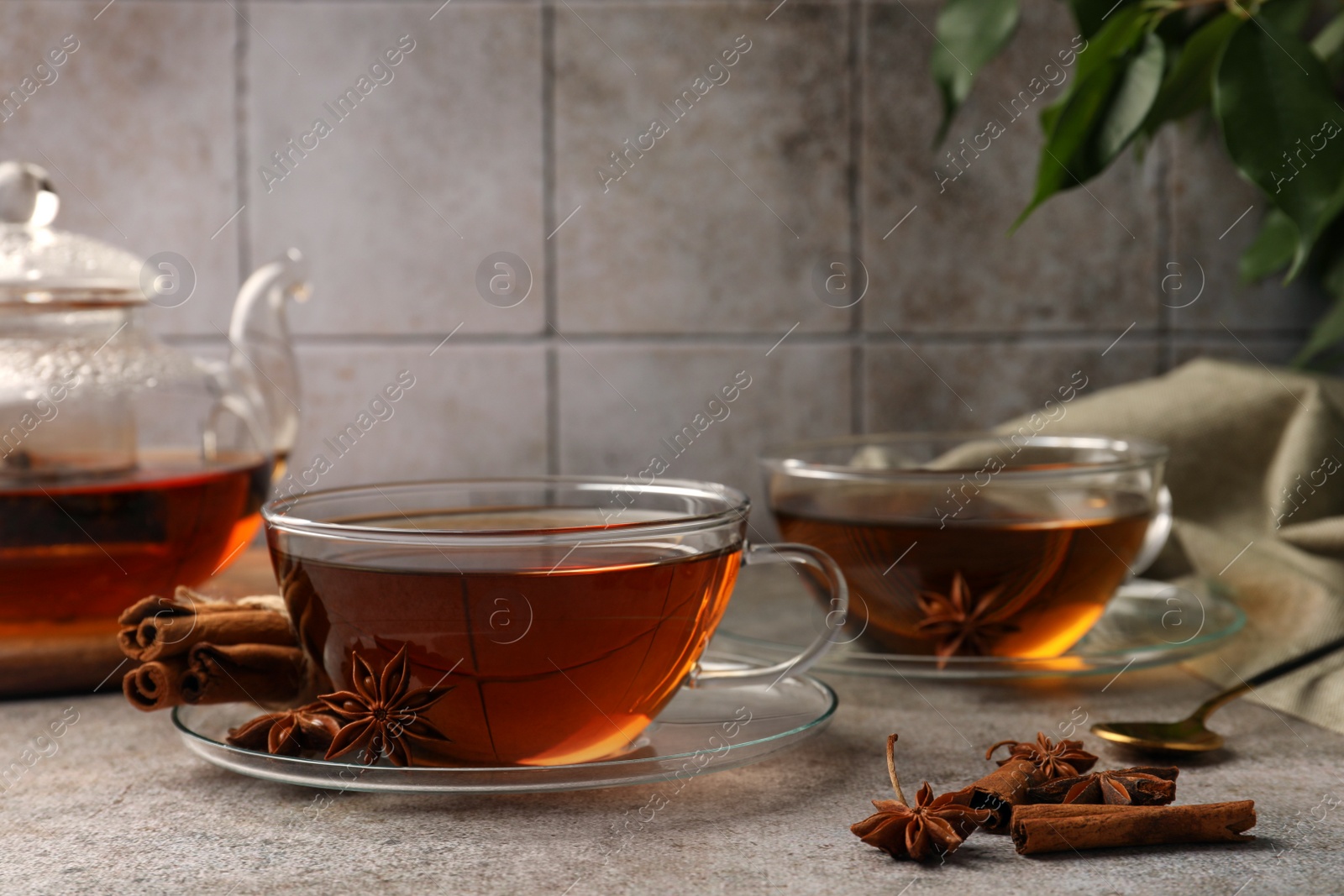 Photo of Aromatic tea with anise stars and cinnamon sticks on light grey table. Space for text