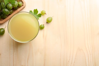 Photo of Tasty gooseberry juice on wooden table, flat lay. Space for text