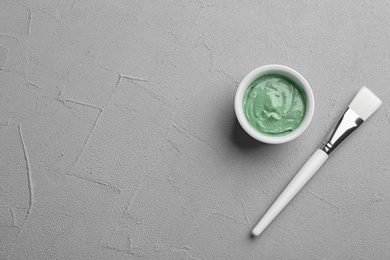 Spirulina facial mask and brush on light grey table, flat lay. Space for text