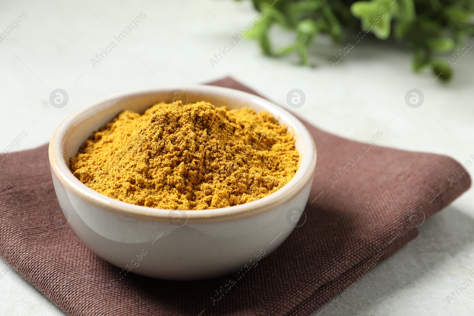 Photo of Curry powder in bowl on white table, closeup