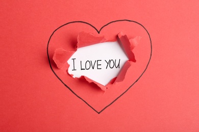 Photo of Phrase I Love You under red torn paper with drawn heart symbol, top view