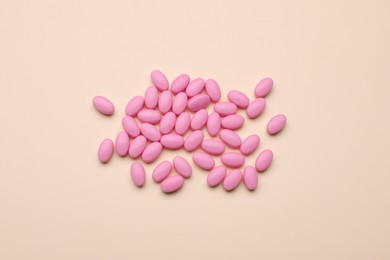 Photo of Many pink dragee candies on yellow background, flat lay