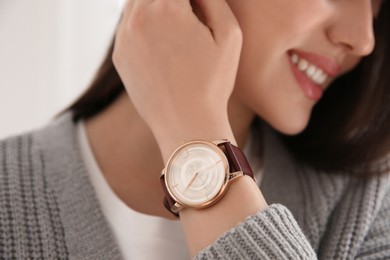 Woman with luxury wristwatch on light background, closeup