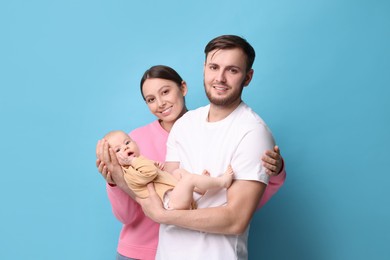 Happy family. Parents with their cute baby on light blue background