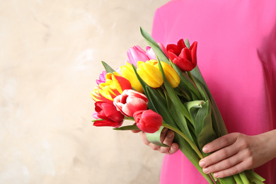 Woman holding beautiful spring tulips on light background, closeup