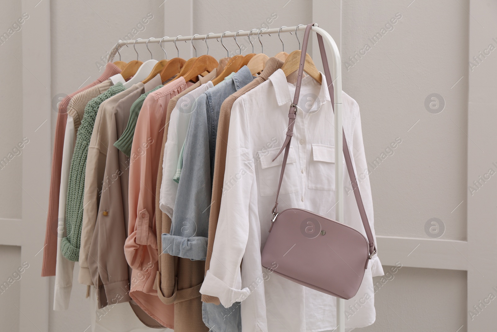 Photo of Rack with stylish women's clothes near light wall