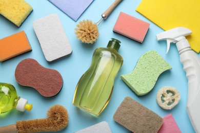 Photo of Flat lay composition with sponges and other cleaning supplies on light blue background