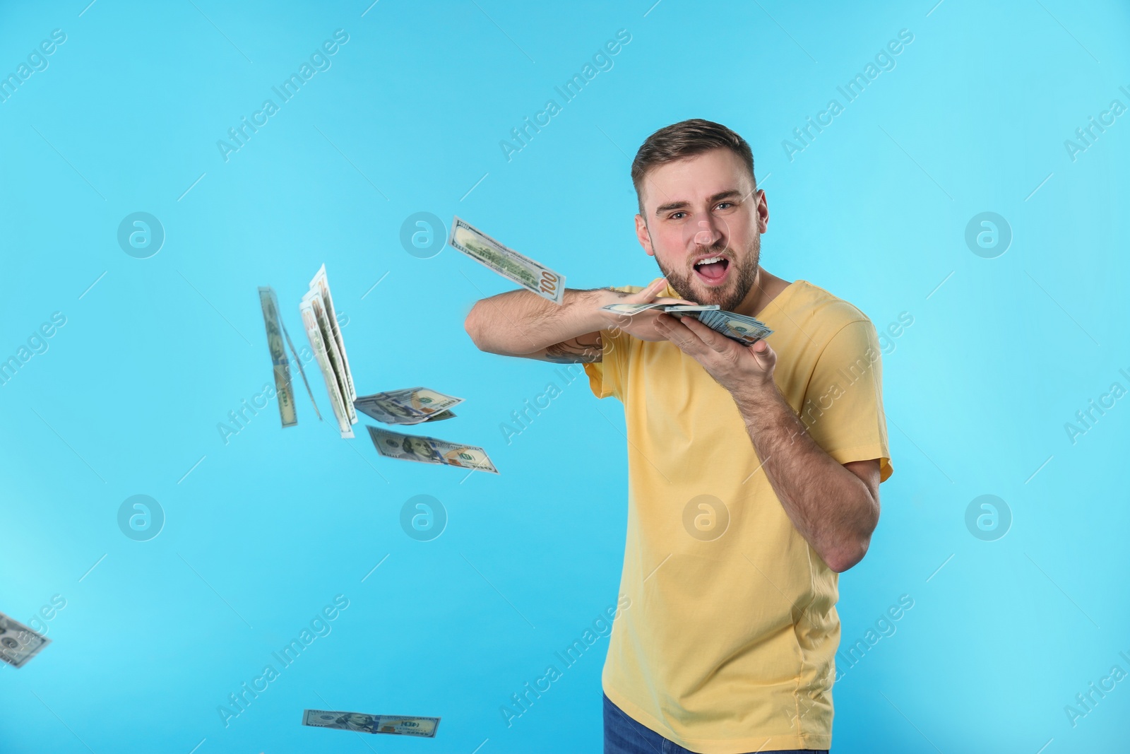 Photo of Happy young man throwing money on color background