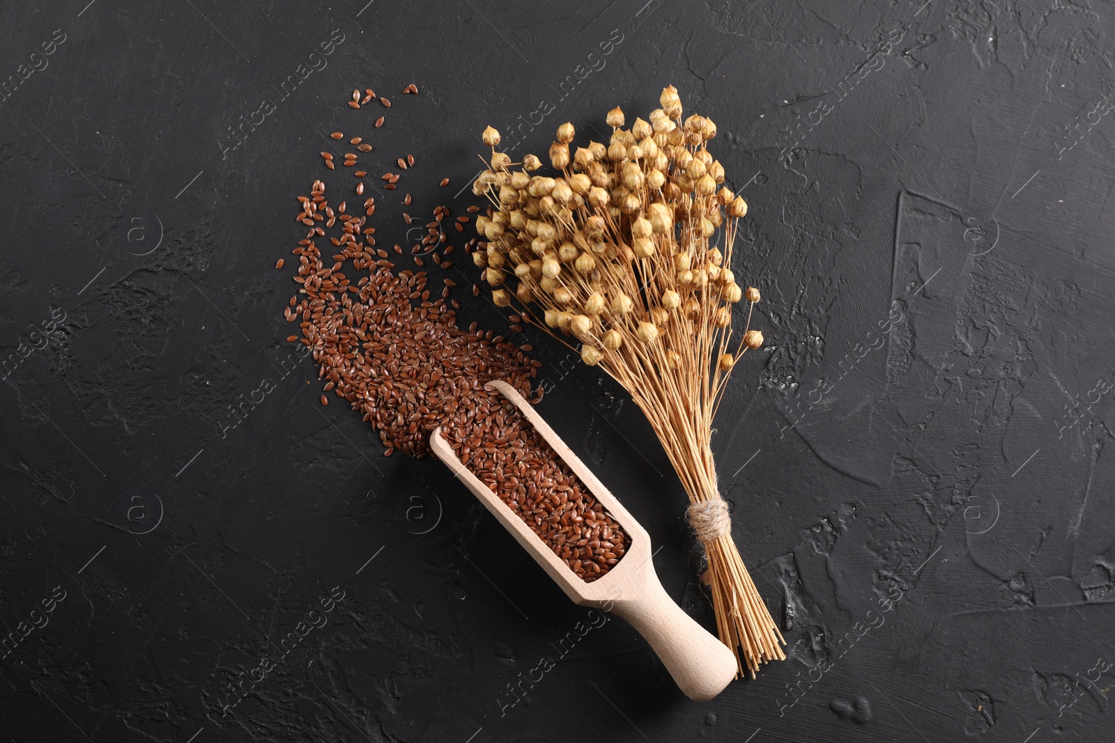 Photo of Flax seeds and dry flowers on grey textured table, flat lay