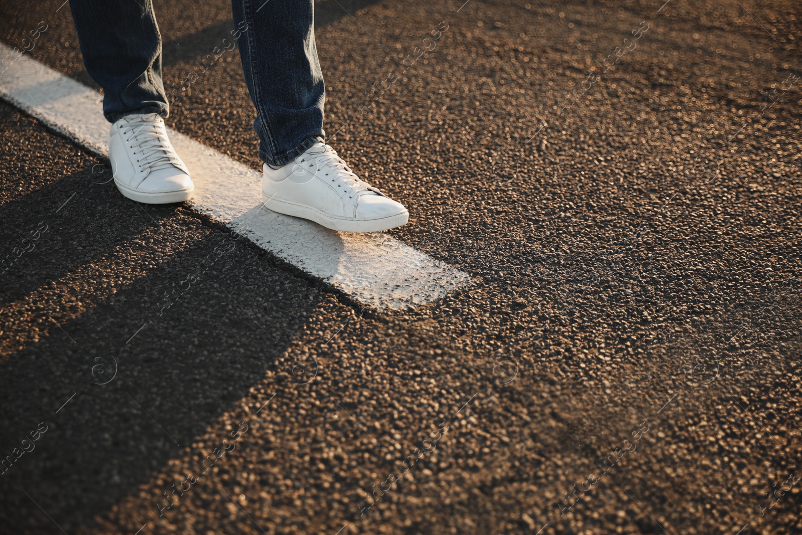 Photo of Man walking along white line on road, closeup with space for text. Way concept