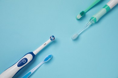 Photo of Electric and plastic toothbrushes on turquoise background, flat lay