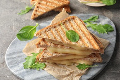 Photo of Marble board with fresh cheese sandwiches on table