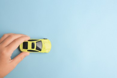 Photo of Child playing with toy car on light blue background, top view. Space for text