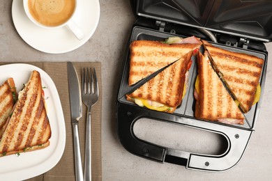 Photo of Modern grill maker with tasty sandwiches on light grey table, flat lay