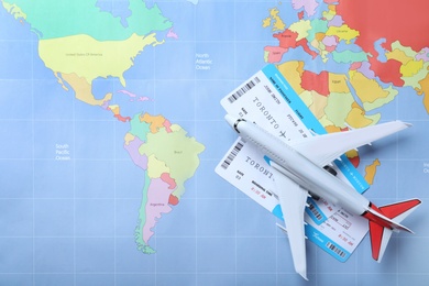 Photo of Toy airplane and tickets on world map, flat lay. Travel agency concept