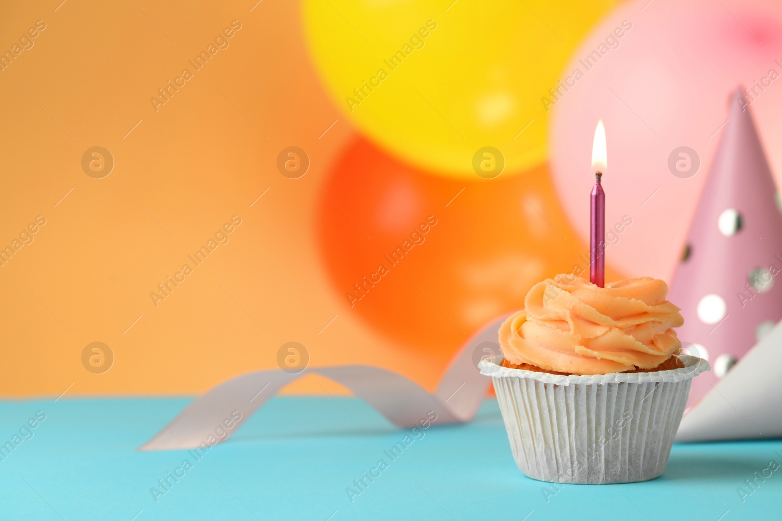 Photo of Tasty birthday cupcake with candle on light blue table. Space for text