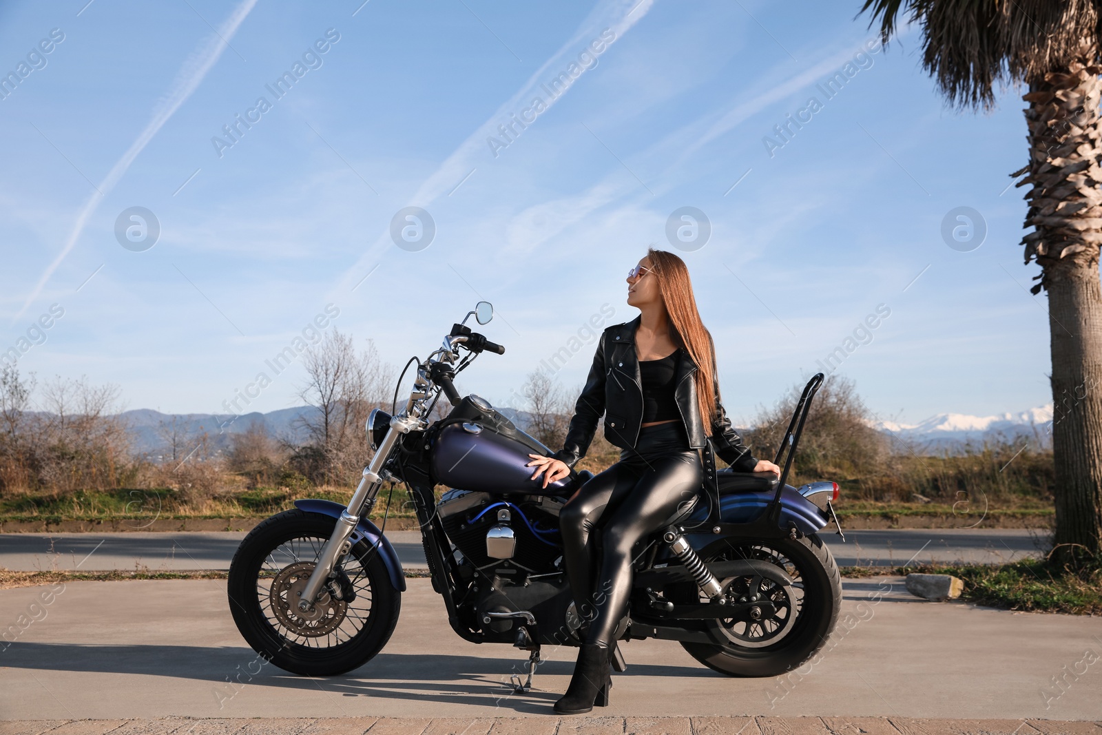 Photo of Beautiful young woman sitting on motorcycle outdoors