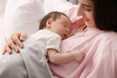 Photo of Mother with her sleeping newborn baby in bed