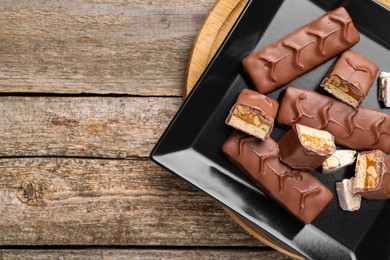 Photo of Tasty chocolate bars with nougat and nuts on wooden table, top view. Space for text