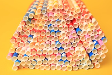 Photo of Many paper drinking straws on yellow background, closeup