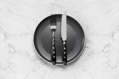 Photo of Clean plate with shiny silver cutlery on white marble table, top view. Space for text