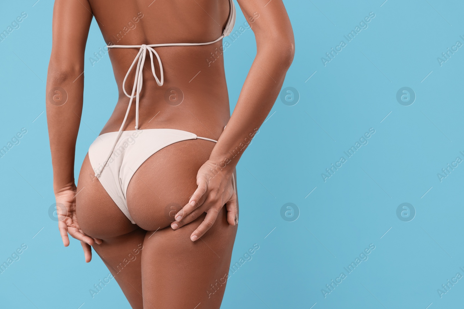 Photo of Woman in stylish bikini on light blue background, closeup. Space for text