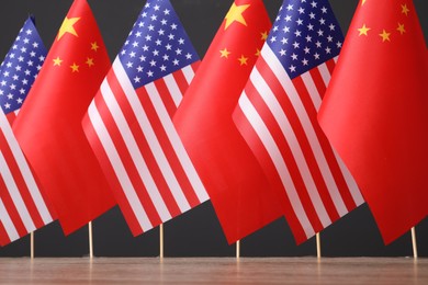Photo of USA and China flags on wooden table against dark background. International relations