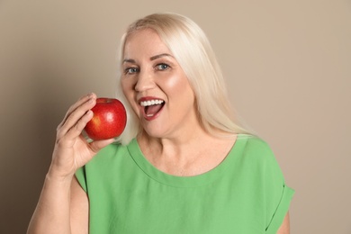 Photo of Smiling woman with perfect teeth and red apple on color background