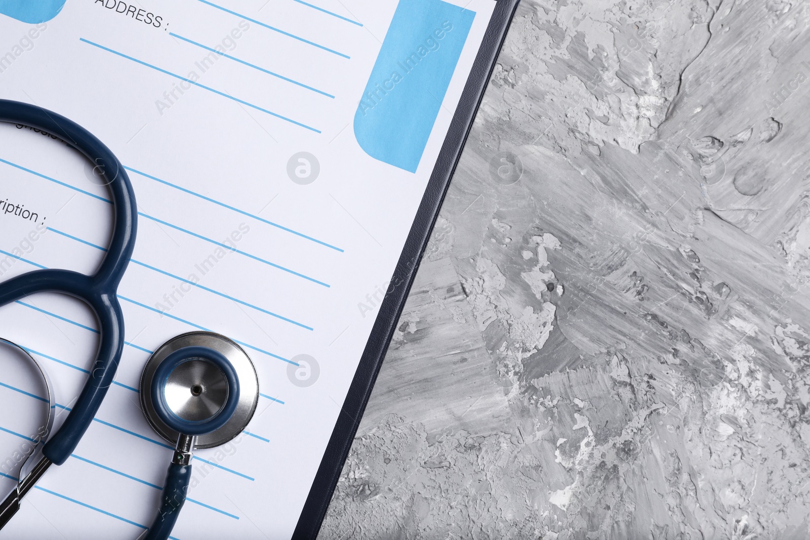 Photo of Medical prescription form with empty fields and stethoscope on grey textured table, top view. Space for text