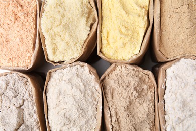 Paper sacks with different types of flour as background, closeup