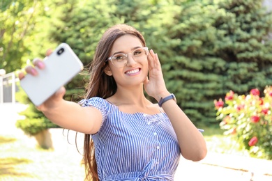 Young woman taking selfie outdoors on sunny day