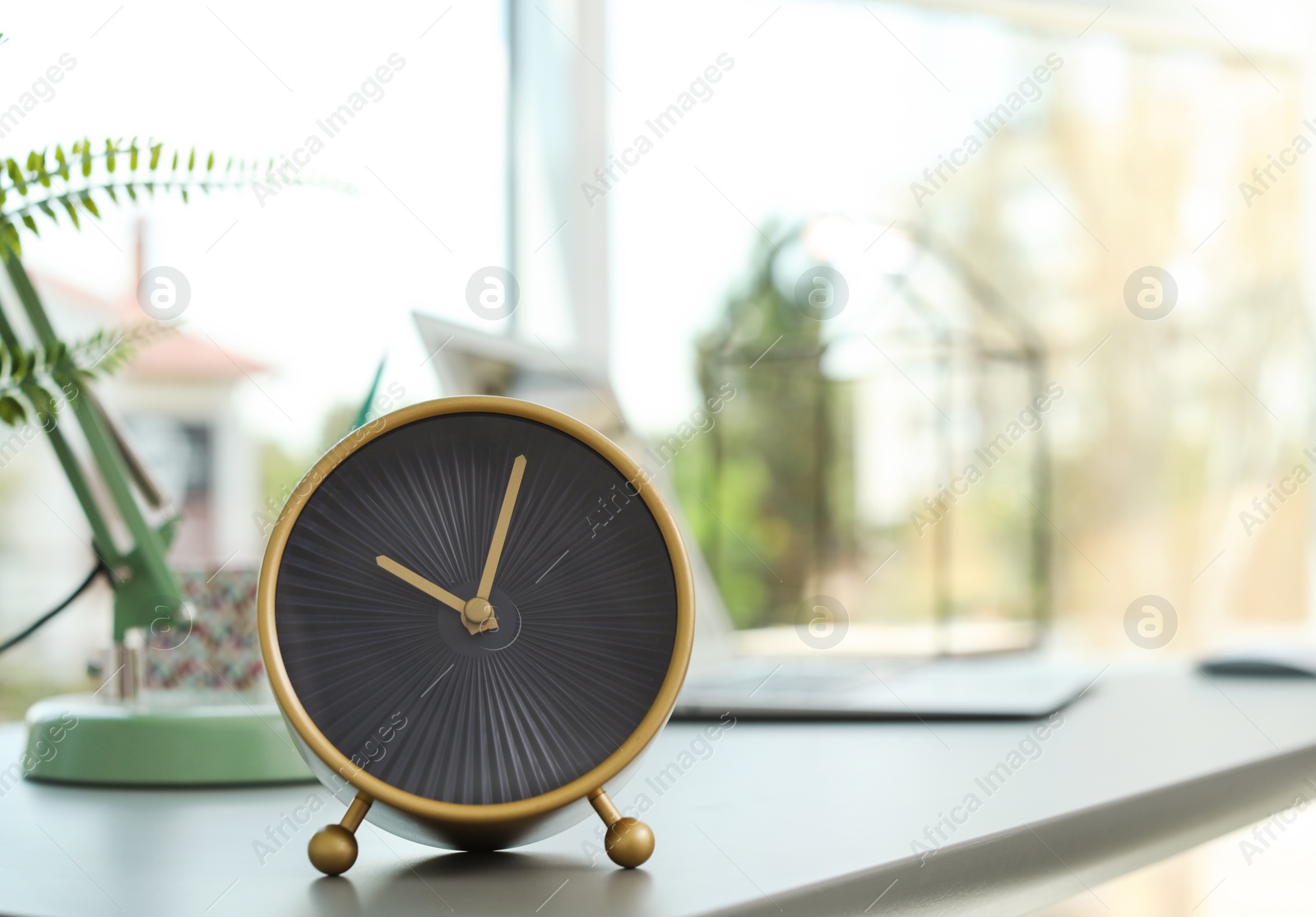 Photo of Analog alarm clock on table in office. Time to work