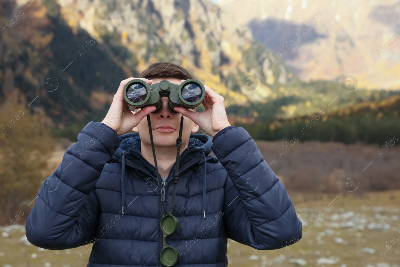 Photo of Boy looking through binoculars in beautiful mountains