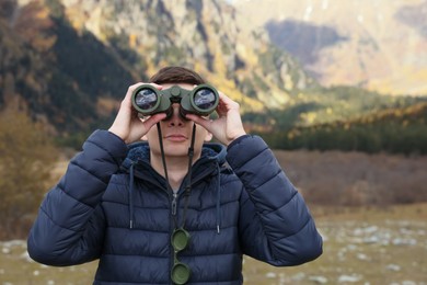 Photo of Boy looking through binoculars in beautiful mountains