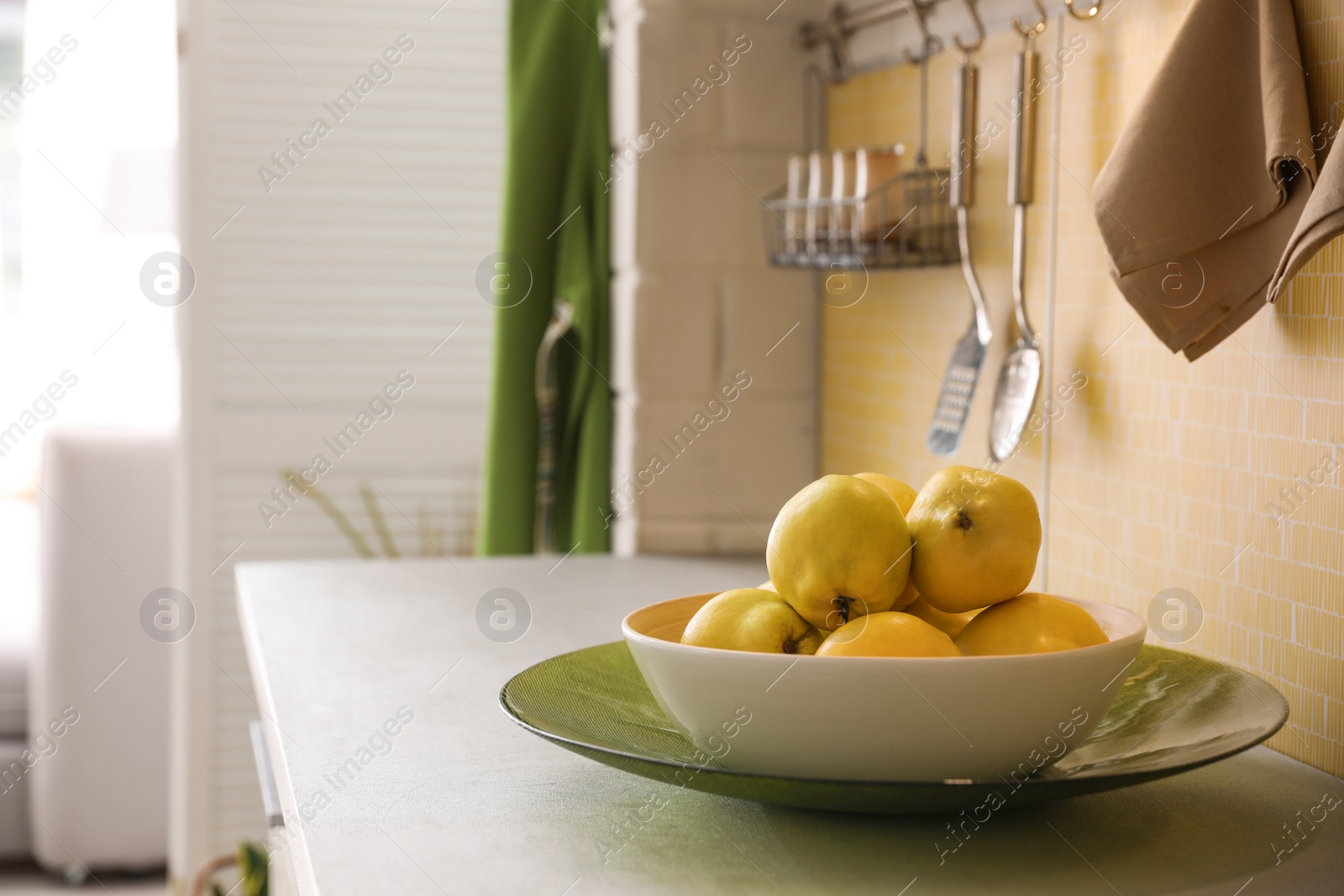 Photo of Plate with ripe quinces on countertop in kitchen. Space for text