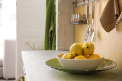 Plate with ripe quinces on countertop in kitchen. Space for text