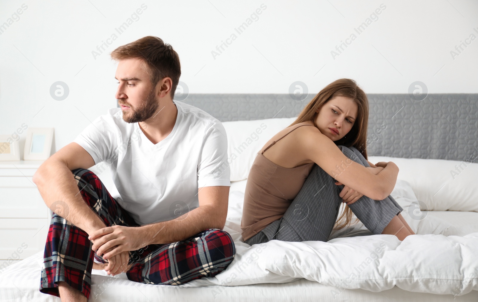 Photo of Unhappy young couple with relationship problems after quarrel in bedroom