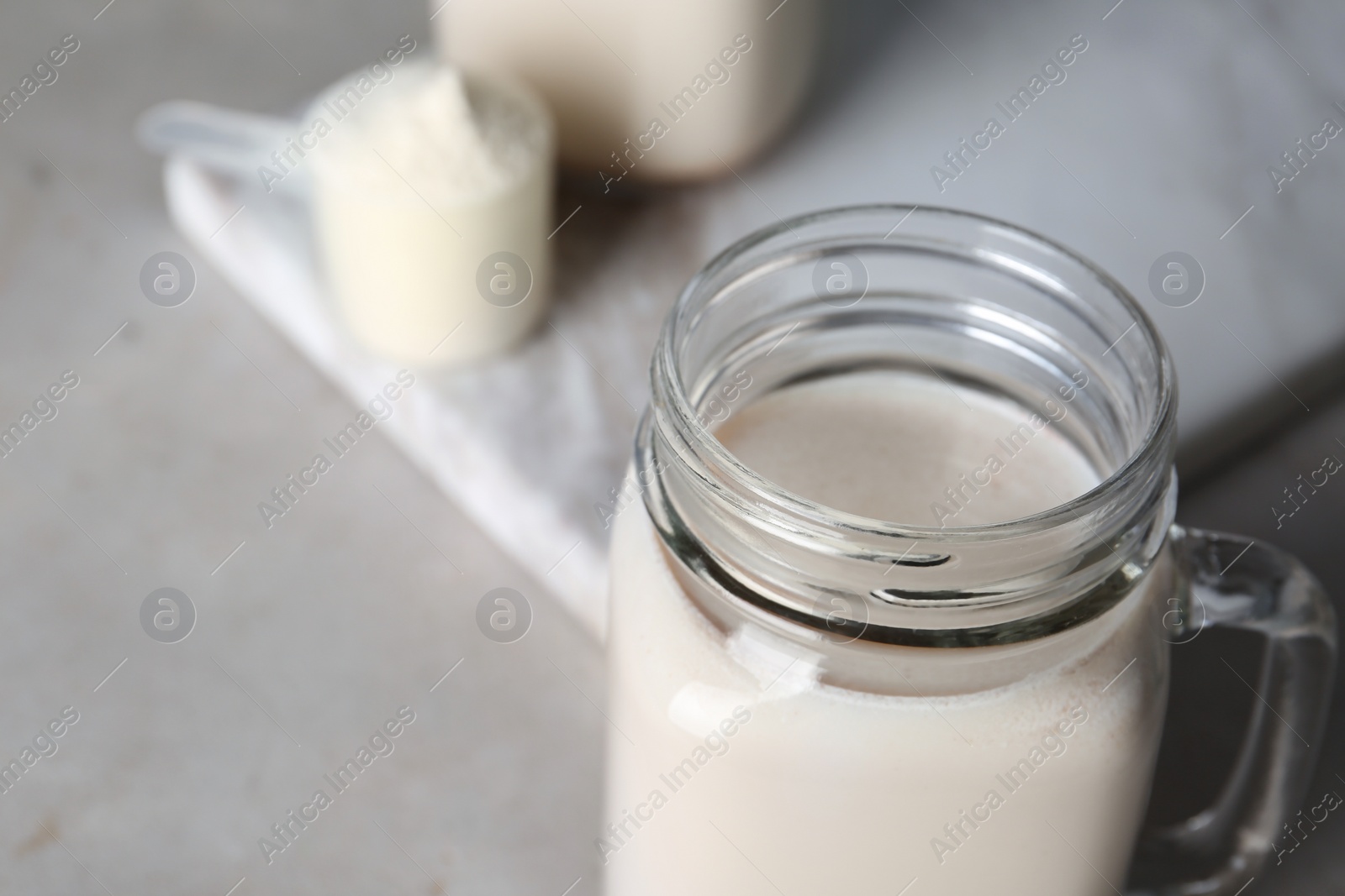 Photo of Mason jar with protein shake on table, closeup. Space for text