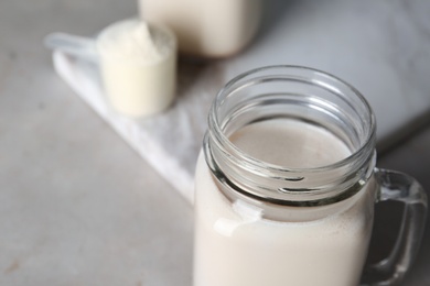 Photo of Mason jar with protein shake on table, closeup. Space for text