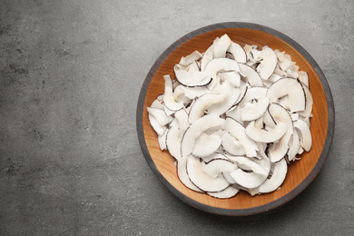 Tasty coconut chips on grey table, top view