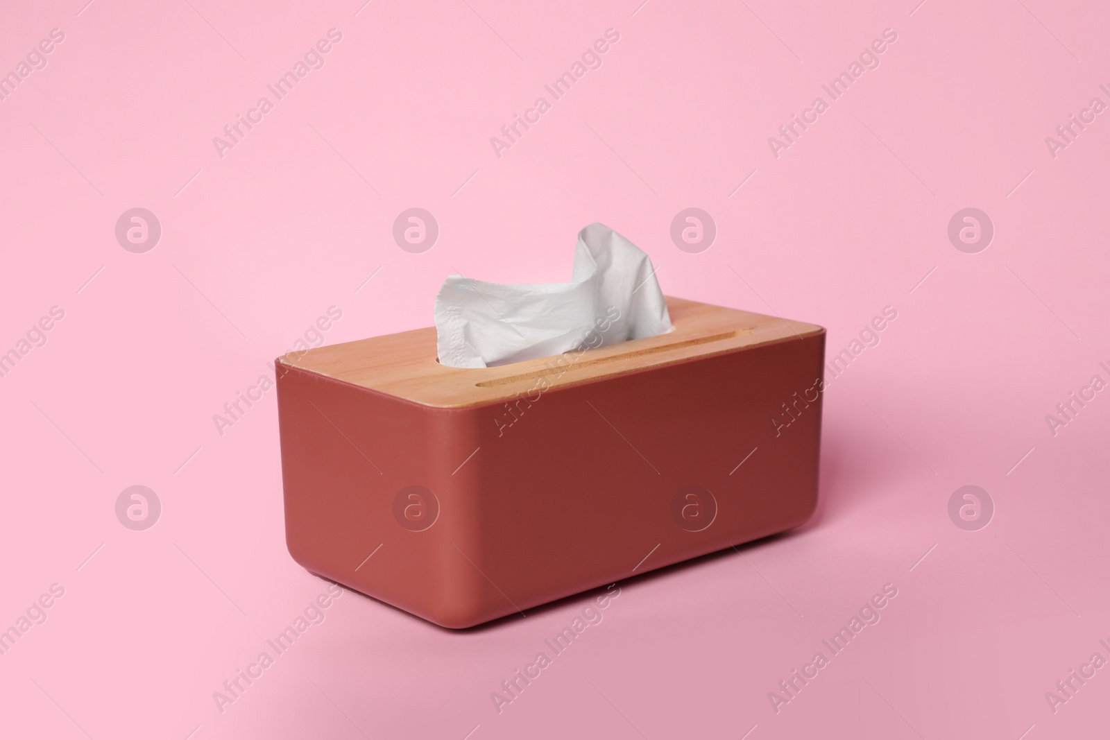 Photo of Holder with paper tissues on pink background