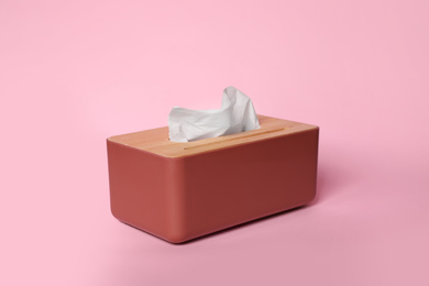 Photo of Holder with paper tissues on pink background