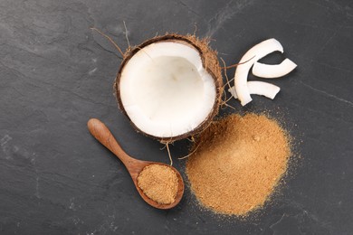 Photo of Coconut sugar, spoon and fruit on dark textured table, flat lay