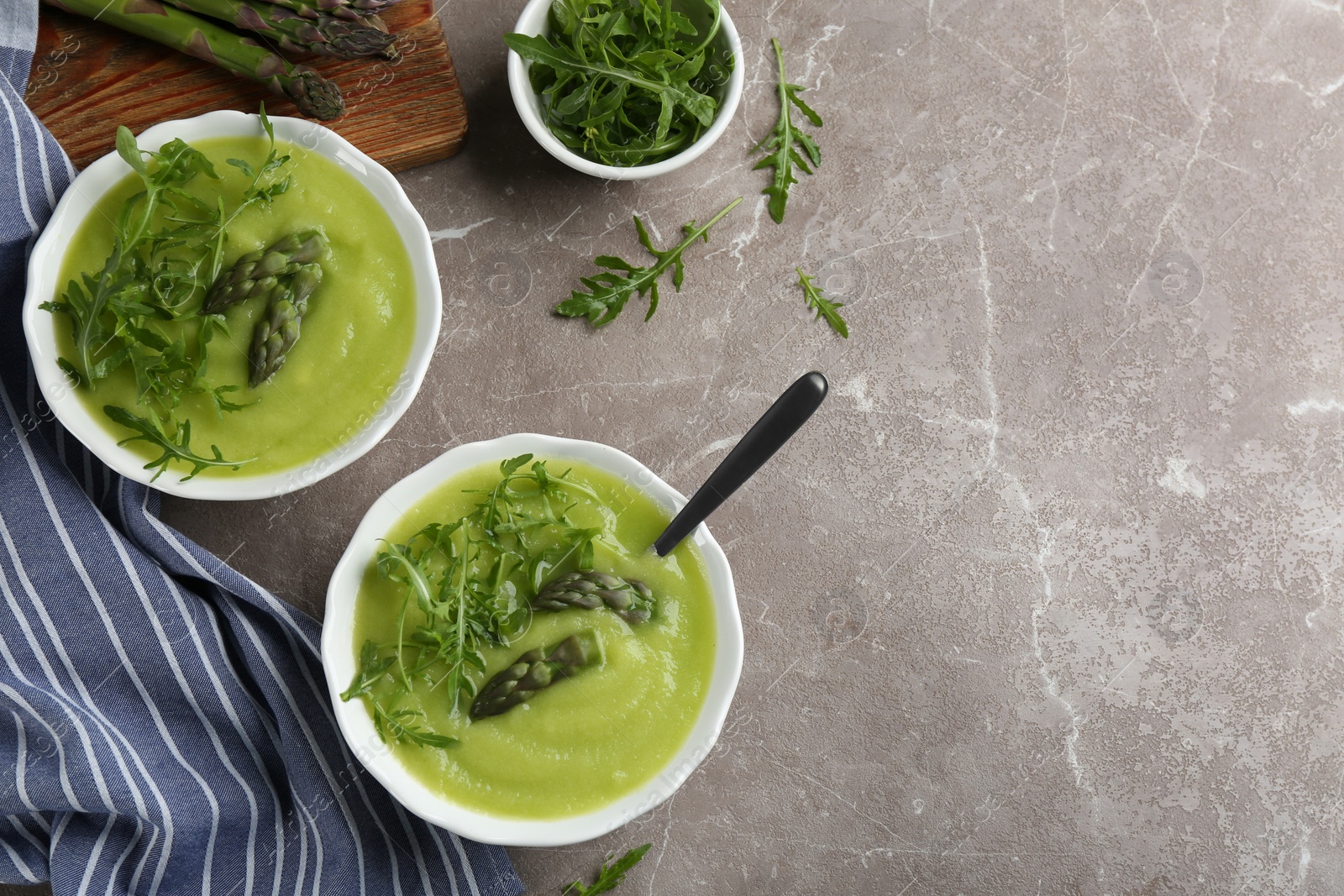 Photo of Delicious asparagus soup served on grey marble table, flat lay. Space for text