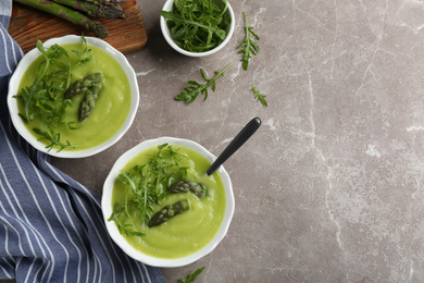 Photo of Delicious asparagus soup served on grey marble table, flat lay. Space for text