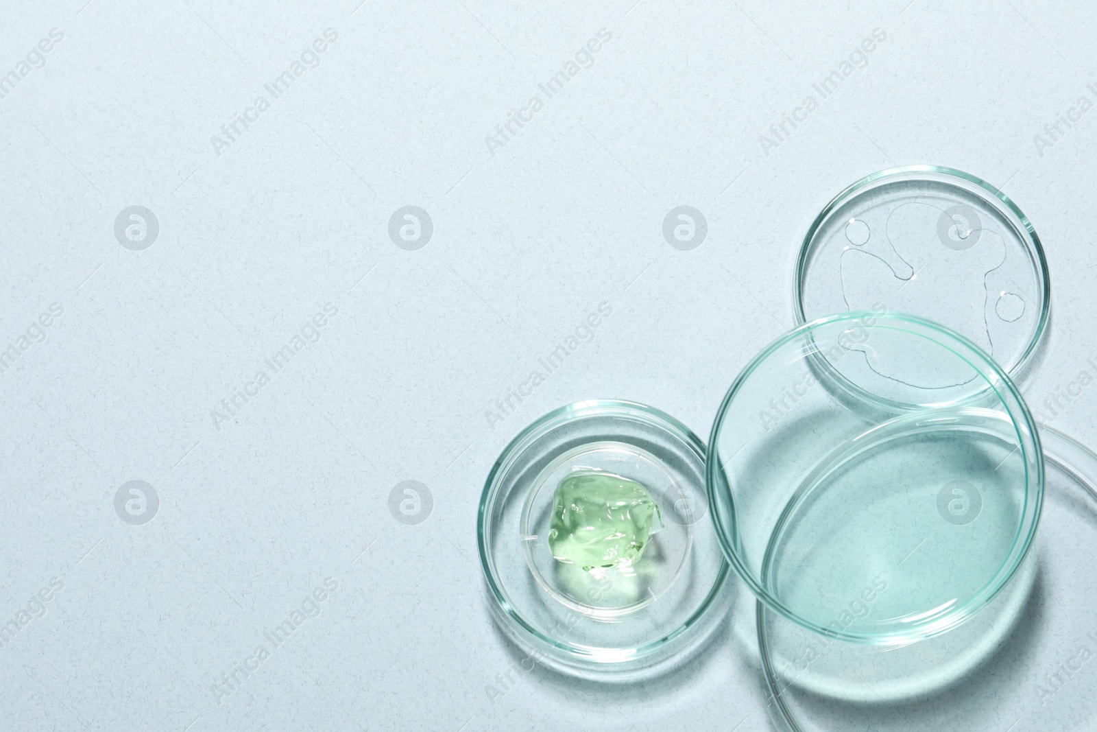 Photo of Organic cosmetic product and laboratory glassware on light background, flat lay. Space for text