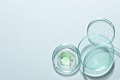 Photo of Organic cosmetic product and laboratory glassware on light background, flat lay. Space for text